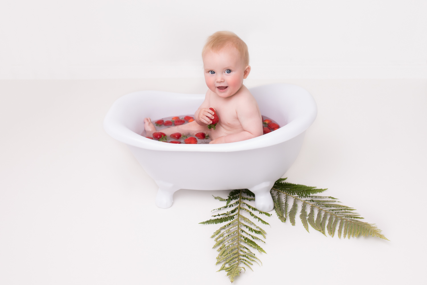 cake smash photography edinburgh, photography of baby boy in bath with strawberries by professional baby photographer Beautiful Bairns Photography Edinburgh