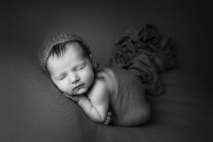 professional newborn baby photo of a newborn baby curled up in dads hands in black and white by professional newborn baby photographer beautiful bairns photography edinburgh