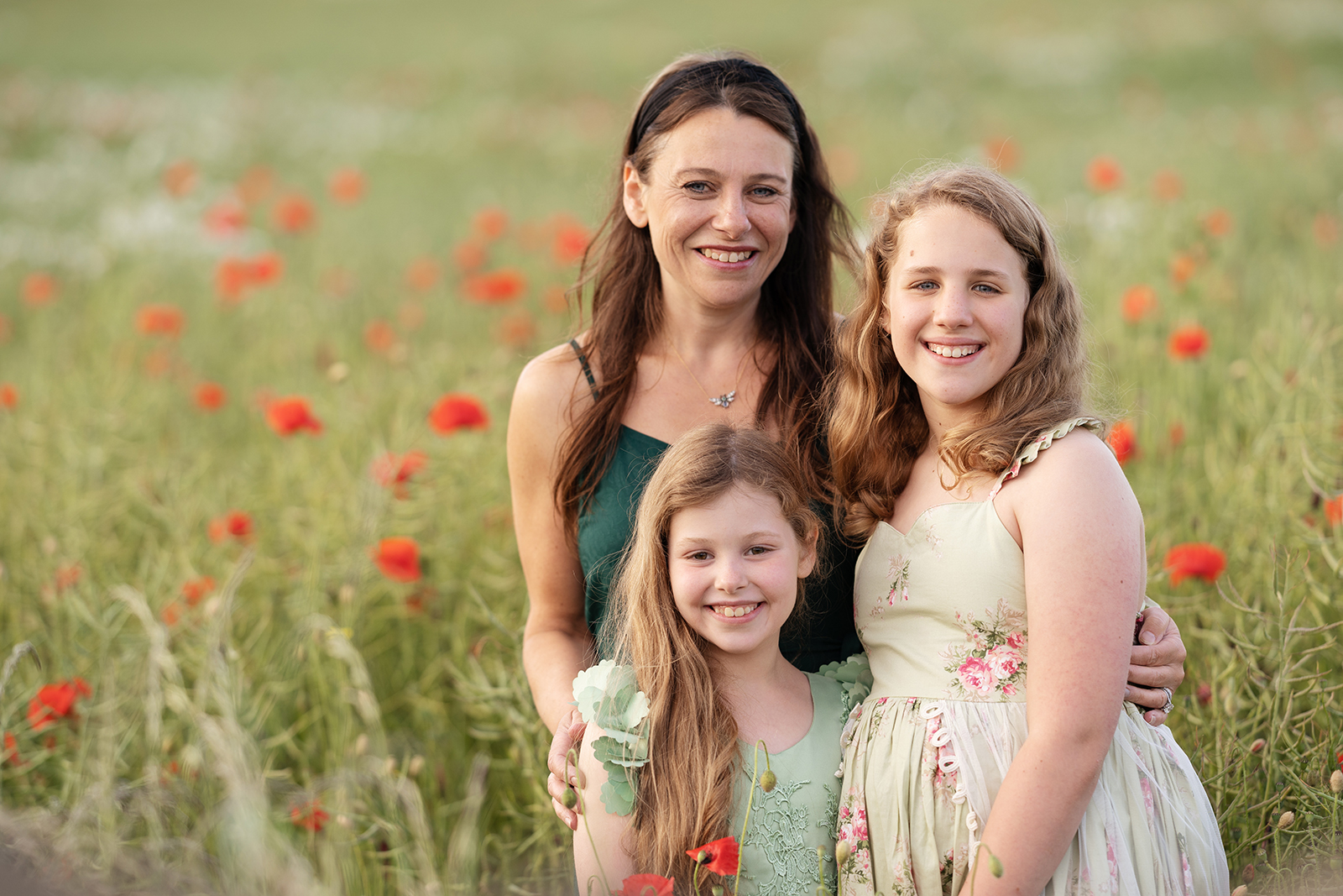 professional family portrait of mum and two daughters embracing in a poppy field outside of Edinburgh by professional family photographer Beautiful Bairns Photography
