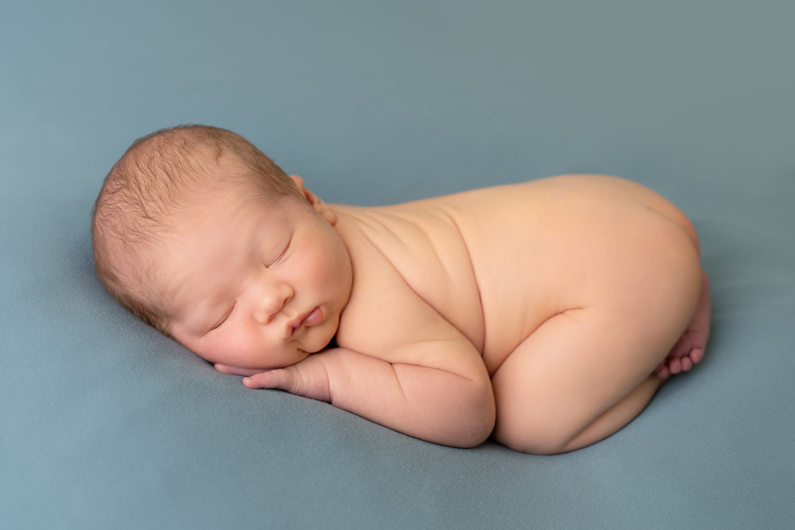 professional newborn photo of newborn baby naked on teal blanket in bum up pose by newborn photographer edinburgh beautiful bairns