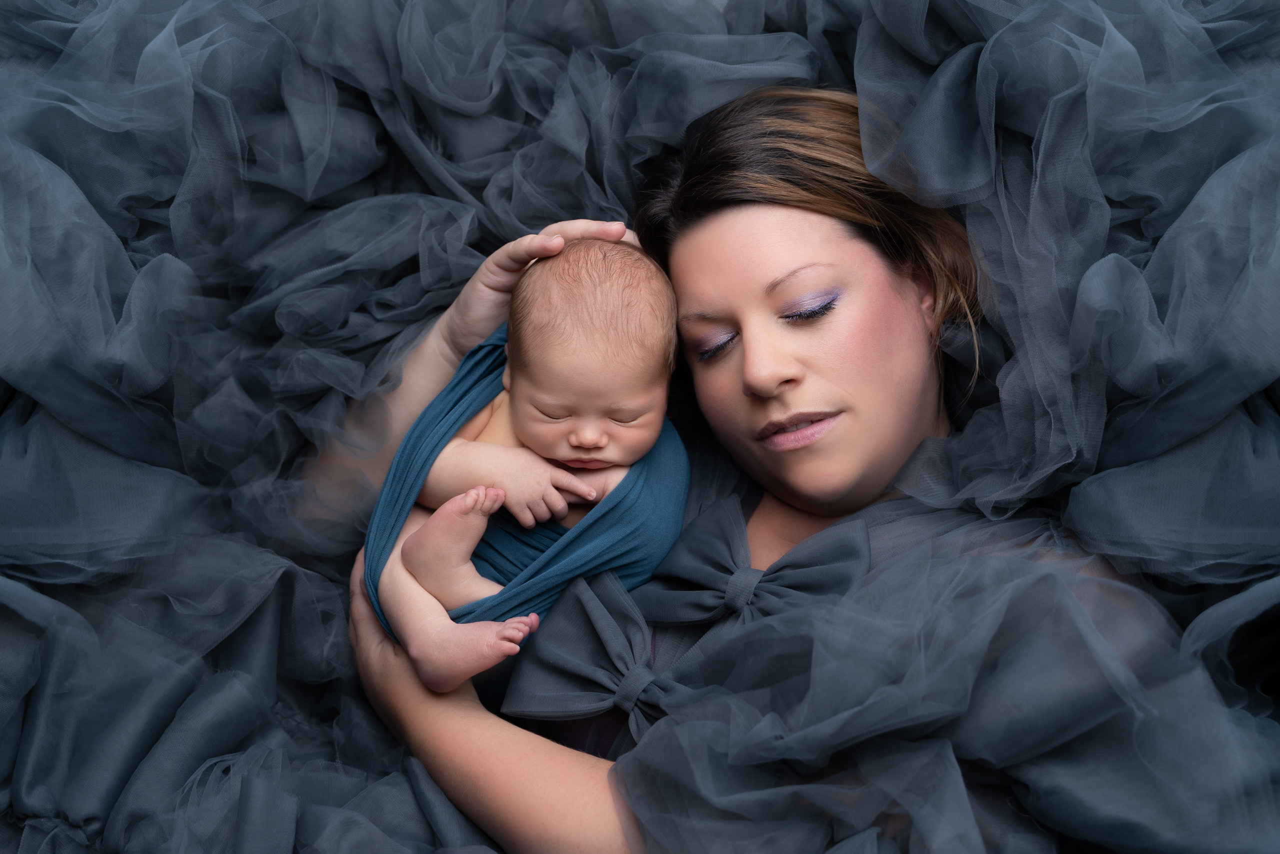 professional photo of mum holding newborn baby surrounded by grey tulle by professional newborn photographer edinburgh beautiful bairns photography