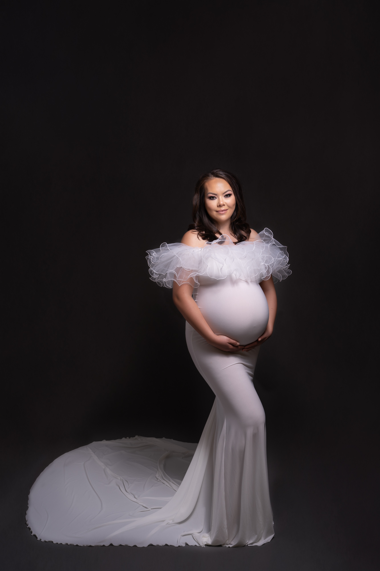 maternity portrait of pregnant woman in white maternity dress on black backdrop