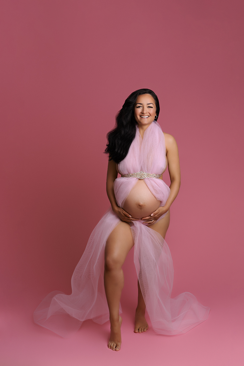 professional maternity photoshoot of pregnant woman wearing pink fabric on a pink backdrop by Edinburgh maternity photographer Beautiful Bairns Photography