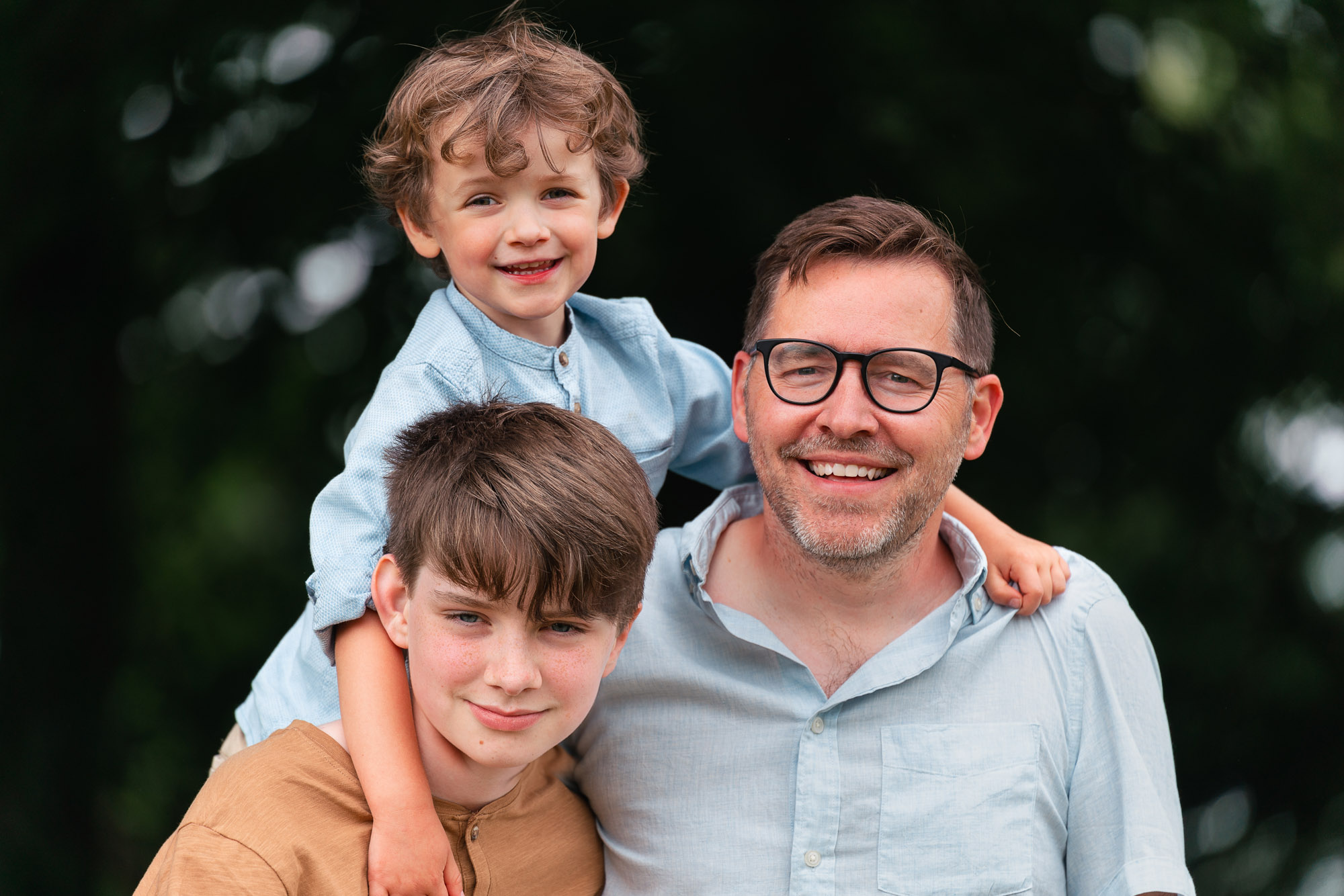 professional family portrait od dad and two sons. All wearing white shirts and denim jeans in front of a grey backdrop. Photograph by Beautiful Bairns photography Edinburgh family photographer