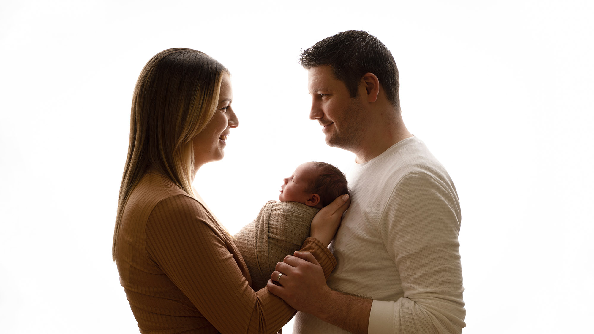 backlit family portrait of newborn baby held by mum and dad by Newborn photographer Edinburgh