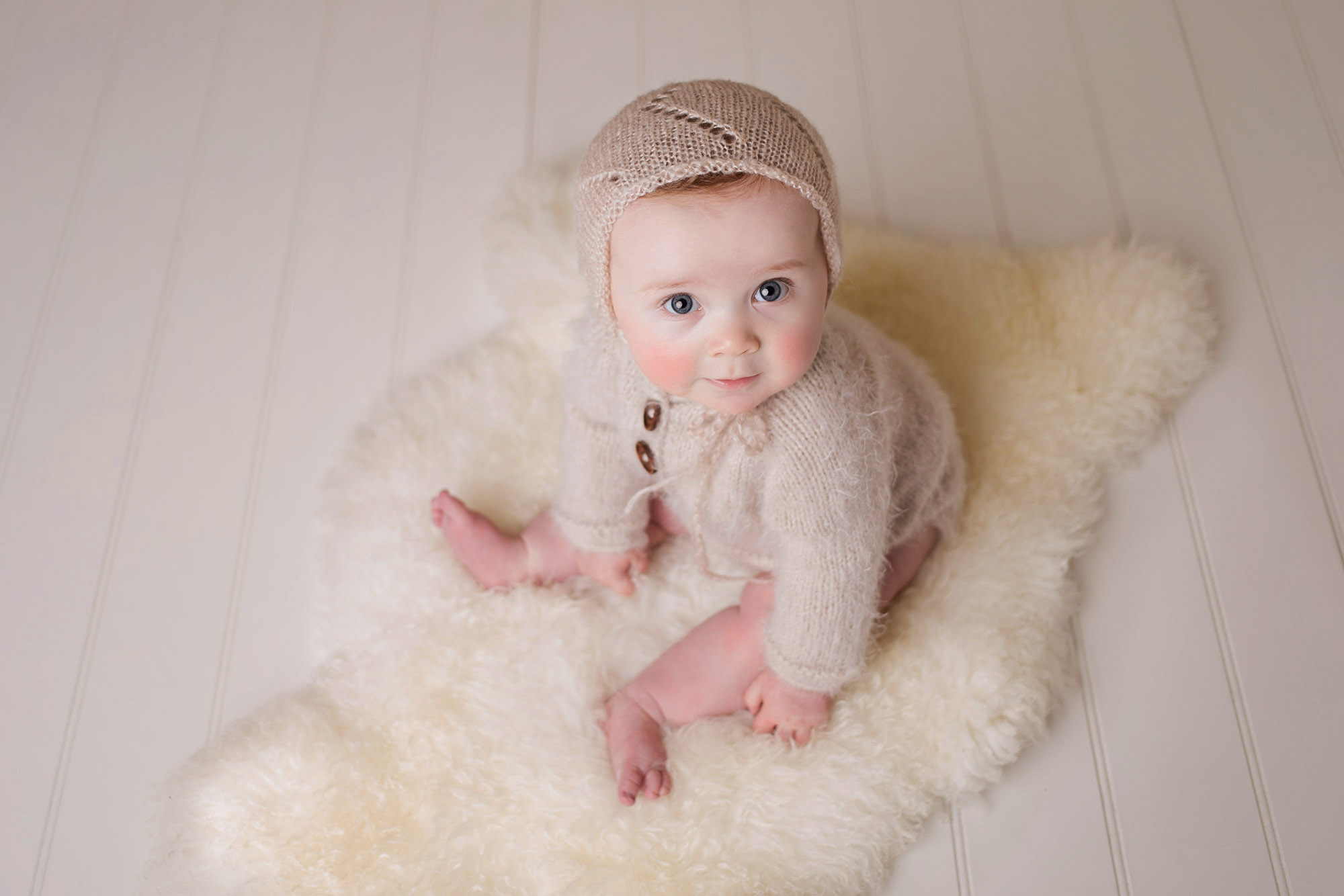 professional baby portrait photo of baby boy in teddy bear outfit sat on wooden bench with teddy bear by baby photographer Beautiful Bairns Photography