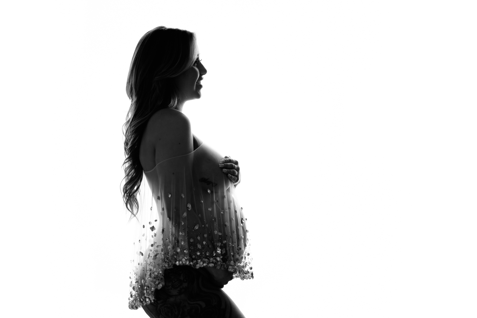 maternity portrait in black and white backlit of pregnant woman in side profile