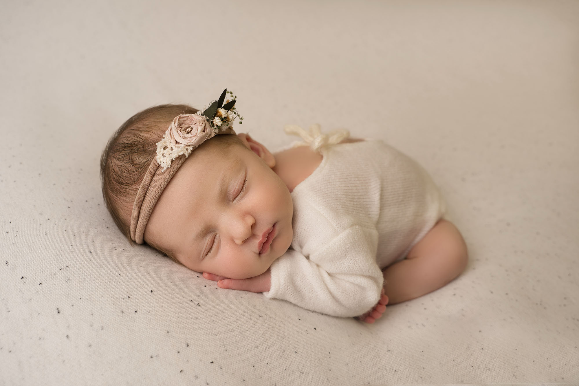 photograph of newborn baby girl wearing a cream vest posed on cream fabric by edinburgh newborn photographer