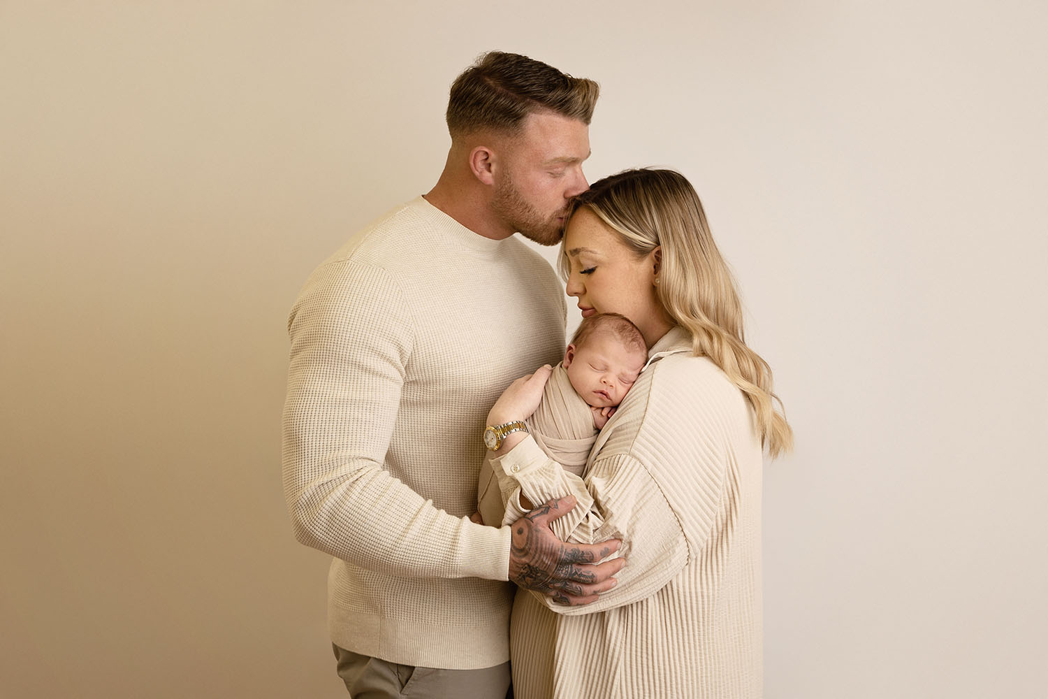 family portrait of mum, dad and baby all wearing cream clothing by edinburgh photographer