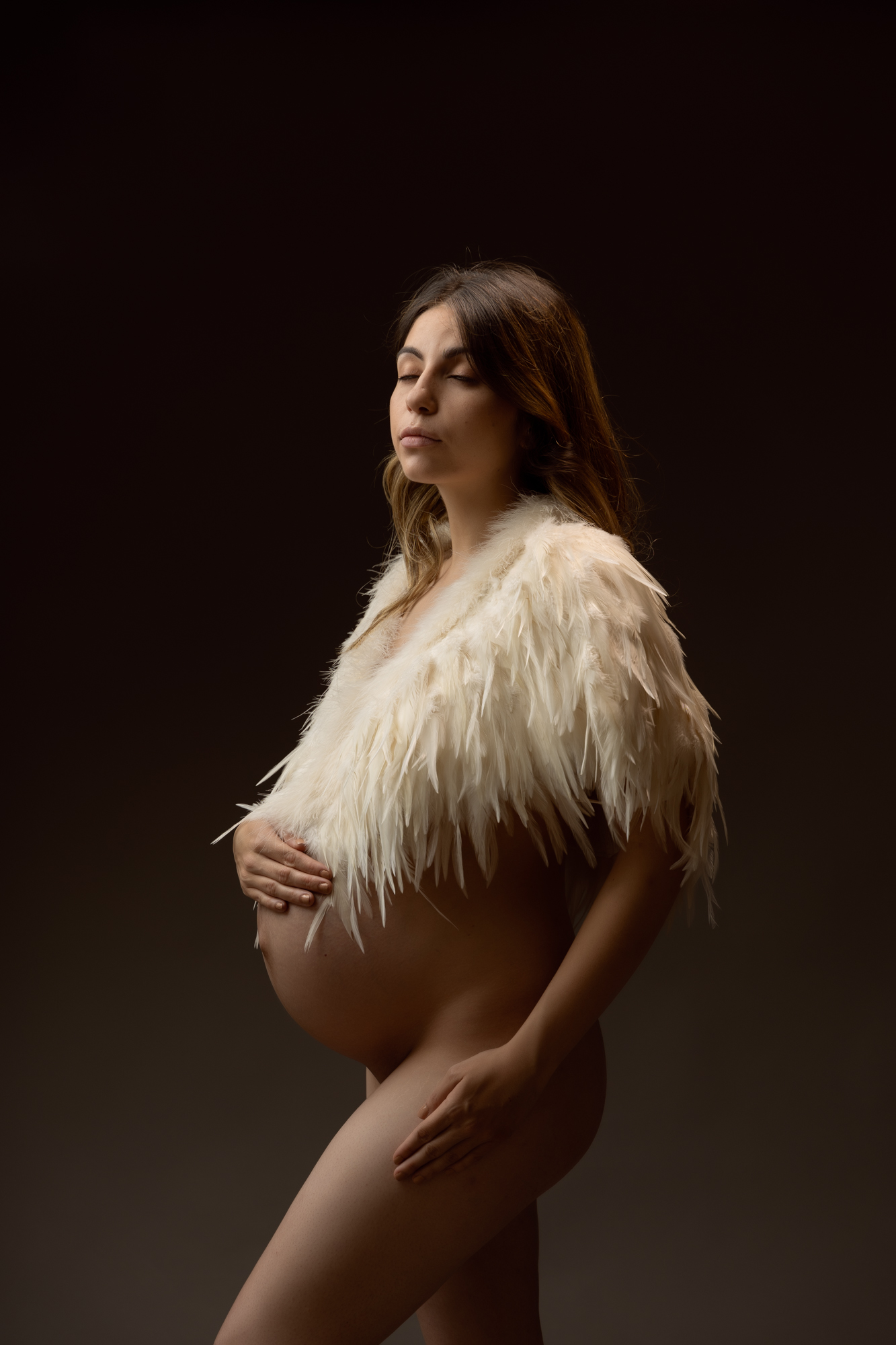 maternity photoshoot image of pregnant woman with feather cape over her bump by edinburgh maternity photographer beautiful bairns photography
